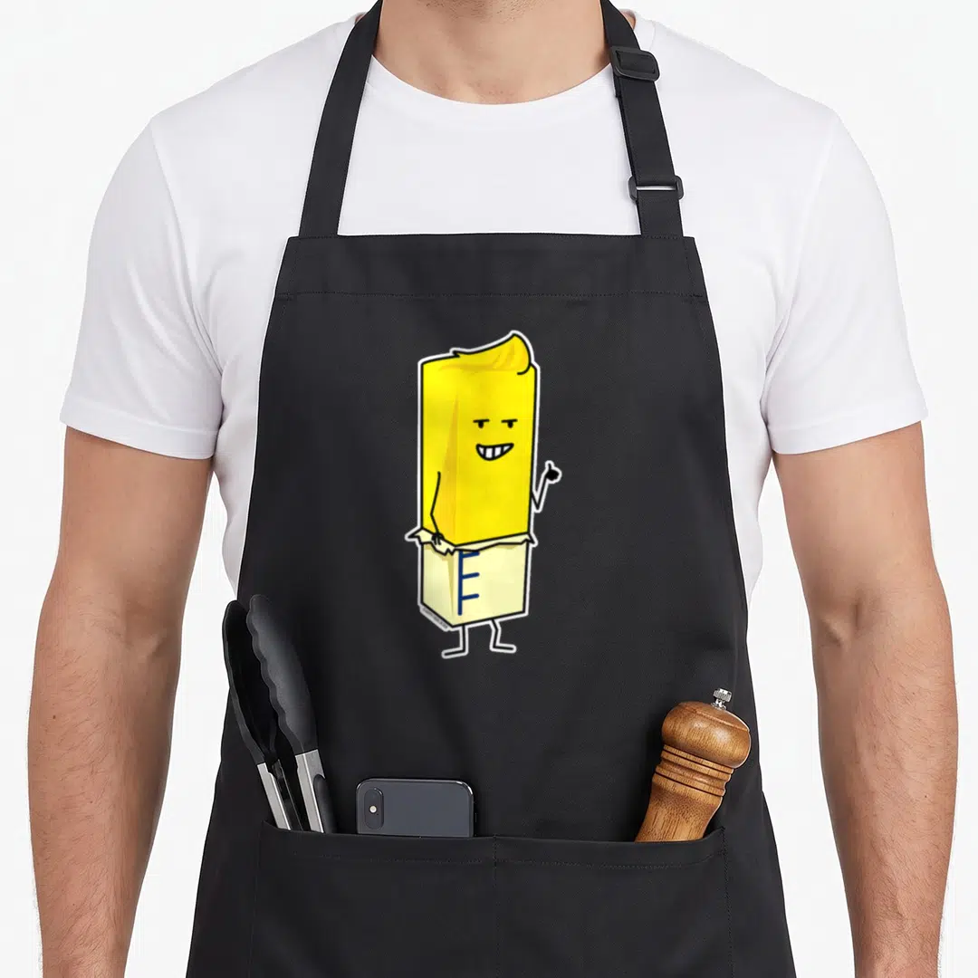 Buttered butter apron - Yellow cartoon butter stick with face and thumbs up inside white wrapper with blue markings — shown on a black cotton canvas apron against a white background