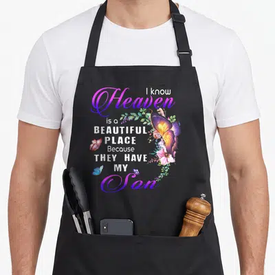 Heaven beautiful apron - Butterfly and floral art with text I know heaven is a beautiful place because they have my son — shown on a black cotton canvas apron against a white background