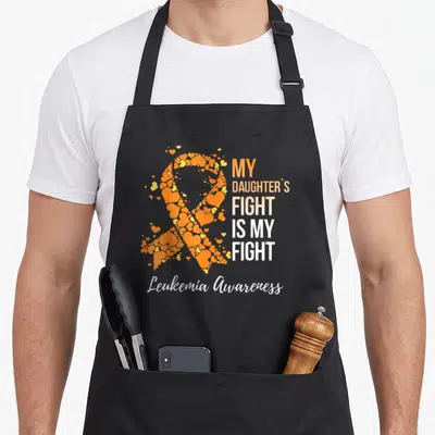 Daughter mothers day apron - Orange ribbon formed by hearts next to My Daughters Fight Is My Fight text and Leukemia — shown on a black cotton canvas apron against a white background