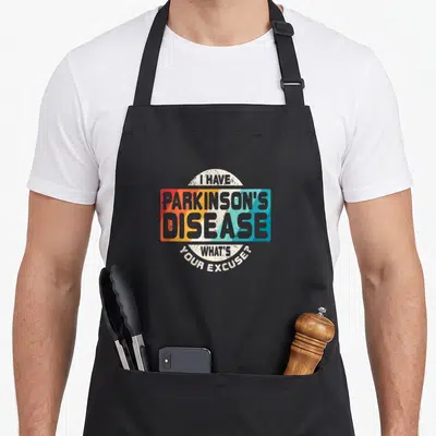 Survivor parkinsons awareness apron - Retro text design with I Have Parkinson's Disease What's Your Excuse over red — shown on a black cotton canvas apron against a white background