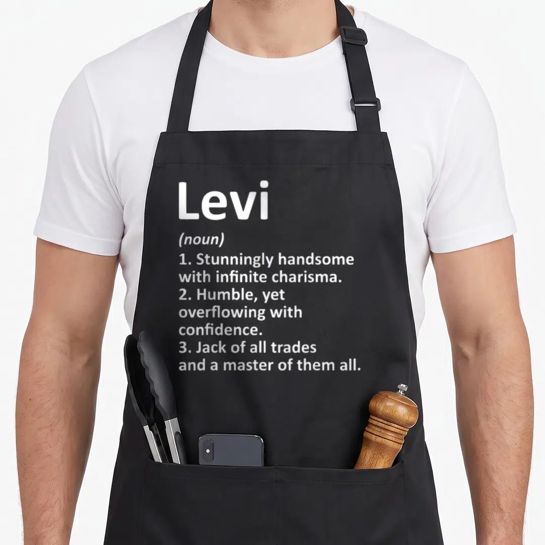 Definition father day aprons - White dictionary style text defining Levi as handsome and a master of all trades — shown on a black cotton canvas apron against a white background
