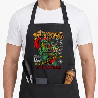 Curve dragon apron - Green dragon coiled around US 129 map with 318 curves text and motorcycles — shown on a black cotton canvas apron against a white background