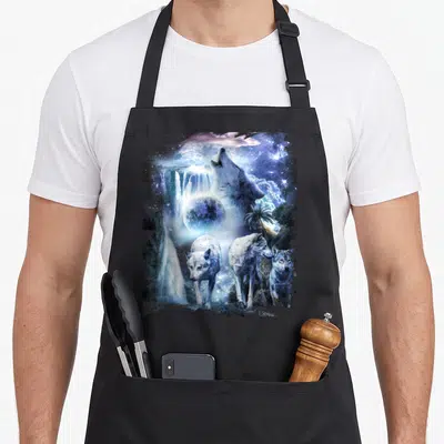 Wolve tropical print aprons - Howling wolf head and three standing wolves with moon, waterfall, and palm trees in blue — shown on a black cotton canvas apron against a white background