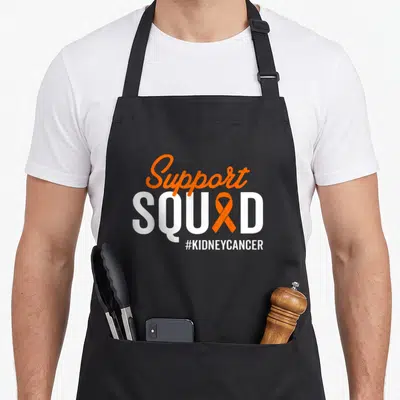 Warrior kidney cancer awareness apron - Support SQU D text with orange ribbon replacing A and hashtag #KIDNEYCANCER — shown on a black cotton canvas apron against a white background