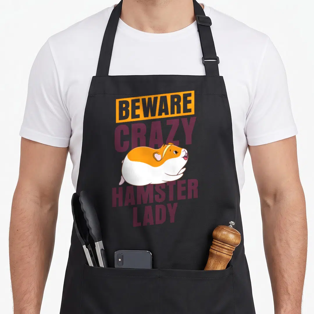 Vintage beware crazy hamster lady apron - Stacked text BEWARE CRAZY HAMSTER LADY with cartoon hamster in orange — shown on a black cotton canvas apron against a white background