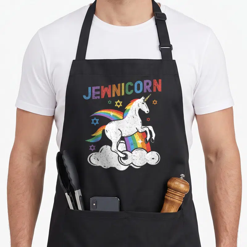 Jewnicorn jewish apron - White unicorn on cloud with rainbow mane and scattered Stars of David under arched — shown on a black cotton canvas apron against a white background