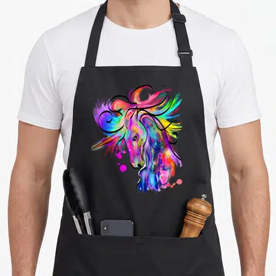 Colourful unicorn apron - Stylized unicorn head composed of pink, blue, yellow, purple, and green watercolor splashes — shown on a black cotton canvas apron against a white background