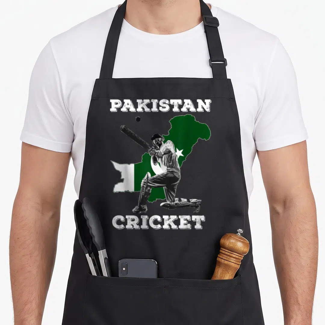 Pakistani cricket apron - Distressed PAKISTAN CRICKET text framing a batter in front of a green and white map silhouette — shown on a black cotton canvas apron against a white background