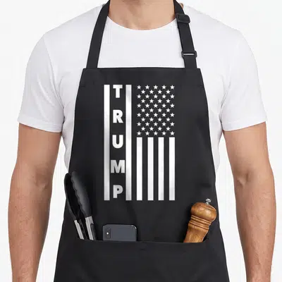 President brittany apron - Vertical TRUMP text integrated into white striped USA flag pattern on grey background — shown on a black cotton canvas apron against a white background