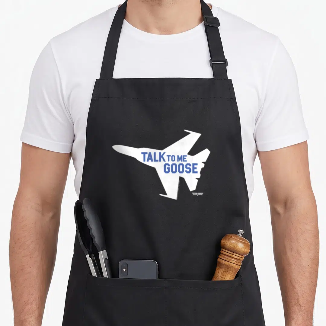 Jet goose apron - White fighter jet silhouette with blue TALK TO ME GOOSE text and small logo watermark — shown on a black cotton canvas apron against a white background