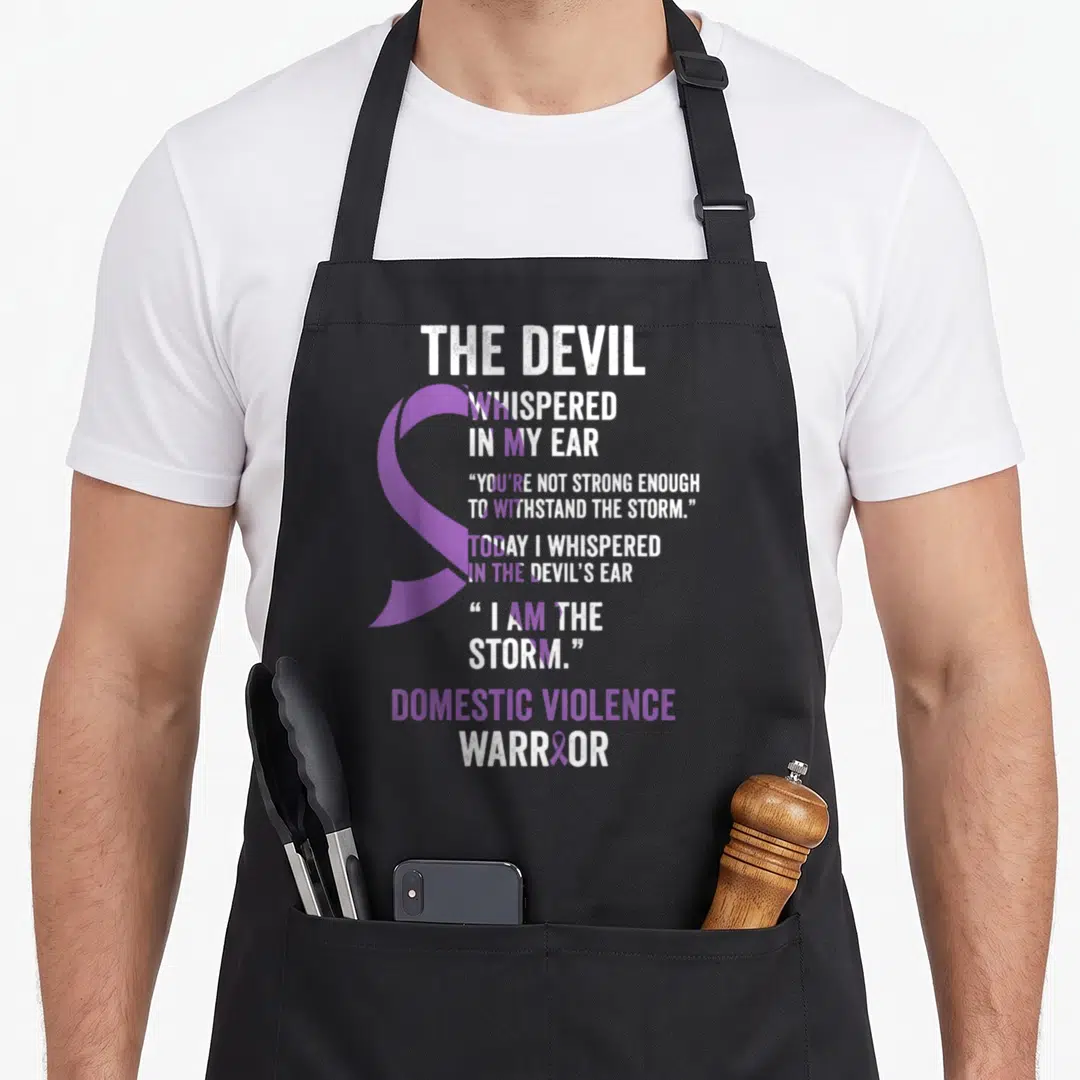 Devil domestic aprons - Purple awareness ribbon overlapping white and purple text reading Devil Whispered In My Ear — shown on a black cotton canvas apron against a white background
