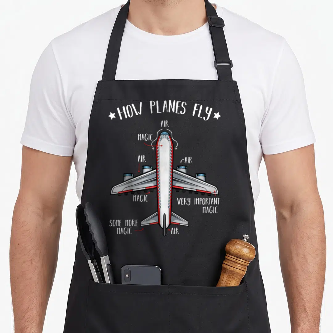 Plane engineering apron - Cartoon airplane diagram with red arrows labeling parts as AIR and MAGIC under title HOW — shown on a black cotton canvas apron against a white background