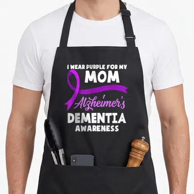 Funny dementia alzheimer's aprons - I Wear Purple For My Mom Alzheimer's Dementia Awareness text with purple ribbon — shown on a black cotton canvas apron against a white background