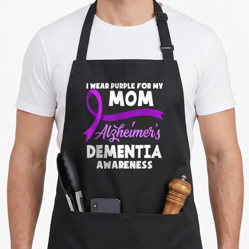 Funny dementia alzheimer's aprons - I Wear Purple For My Mom Alzheimer's Dementia Awareness text with purple ribbon — shown on a black cotton canvas apron against a white background