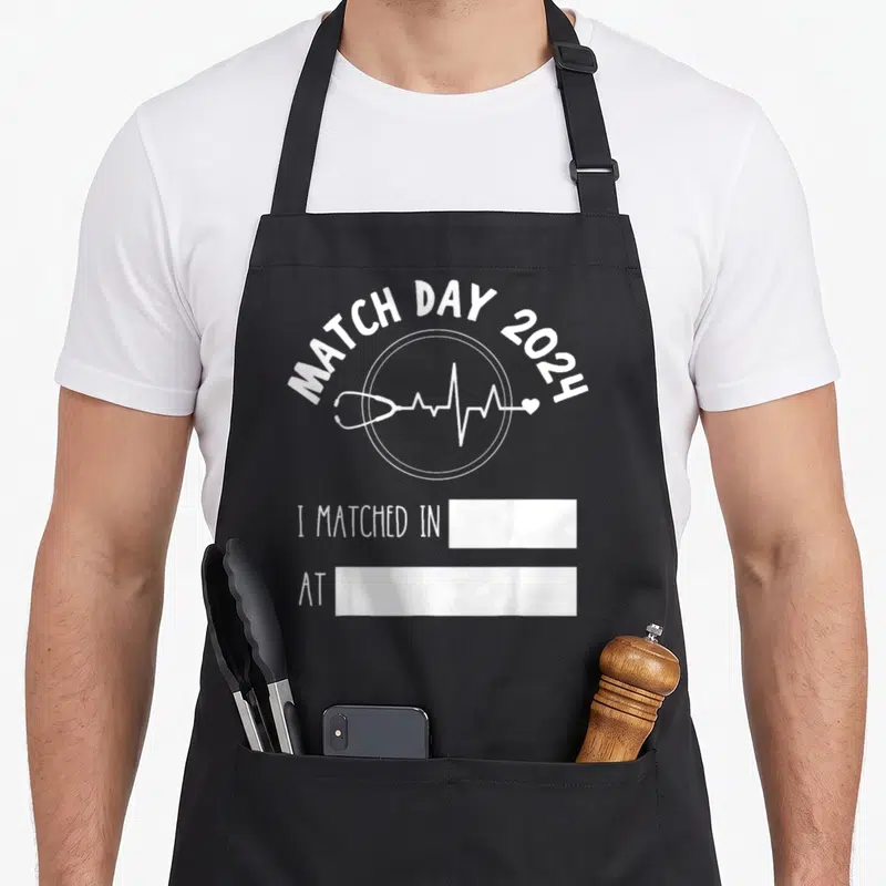 Match doctor apron - White Match Day 2024 text stethoscope EKG line and two fill-in boxes — shown on a black cotton canvas apron against a white background