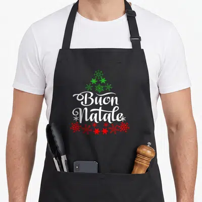 Italian christmas tree apron - Buon Natale white script with green snowflake triangle and red snowflake row — shown on a black cotton canvas apron against a white background