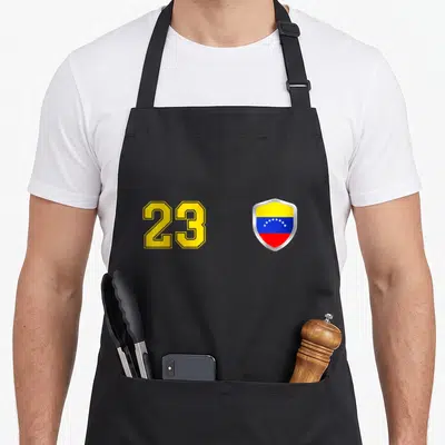 Vinotinto venezuelan boy apron - Number 23 in yellow next to Venezuelan flag shield with yellow blue and red bands — shown on a black cotton canvas apron against a white background