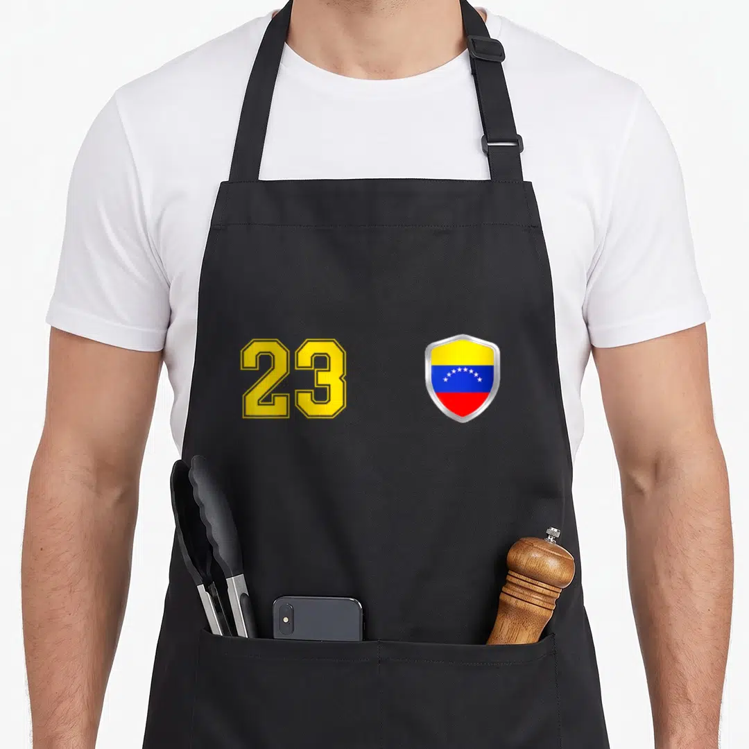 Vinotinto venezuelan boy apron - Number 23 in yellow next to Venezuelan flag shield with yellow blue and red bands — shown on a black cotton canvas apron against a white background