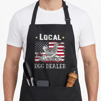 Local chicken egg apron - Distressed US flag with chicken, egg cartons, and LOCAL EGG DEALER text in white, red, blue — shown on a black cotton canvas apron against a white background