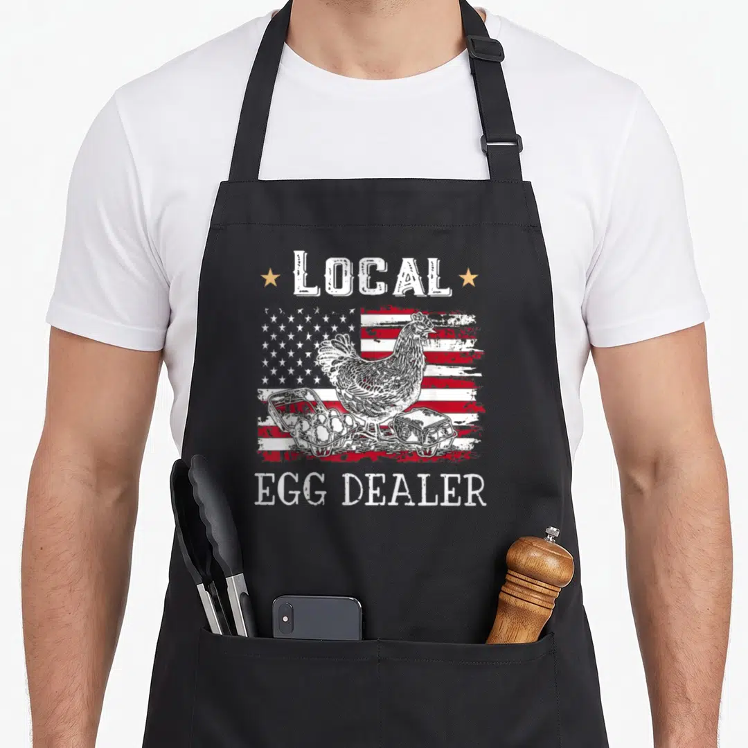 Local chicken egg apron - Distressed US flag with chicken, egg cartons, and LOCAL EGG DEALER text in white, red, blue — shown on a black cotton canvas apron against a white background
