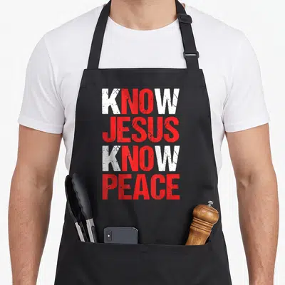 Peace christian apron - Stacked white and red distressed text reading Know Jesus Know Peace — shown on a black cotton canvas apron against a white background