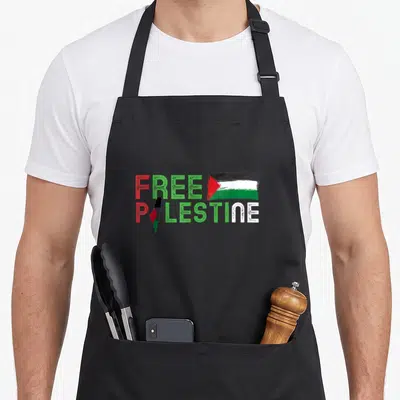 Flag arabic palestinian apron - FREE PALESTINE text with map replacing A and flag graphic in red green white black — shown on a black cotton canvas apron against a white background