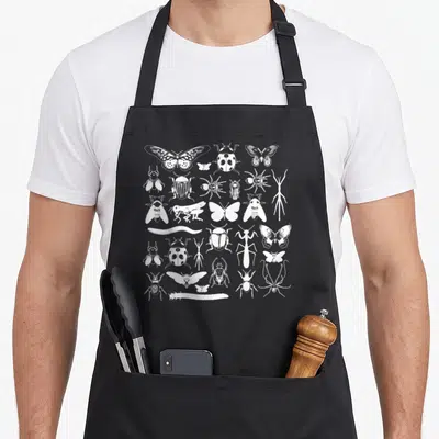 Insect beetle apron - White line art grid of beetles, butterflies, spiders, and stick insects — shown on a black cotton canvas apron against a white background