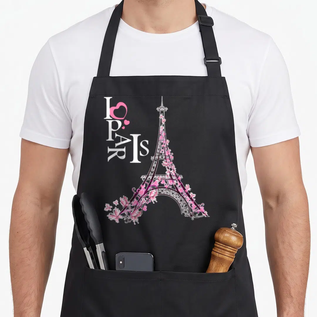 Retro france paris apron - Vertical I PARIS text with pink heart next to a floral Eiffel Tower in pink and black — shown on a black cotton canvas apron against a white background