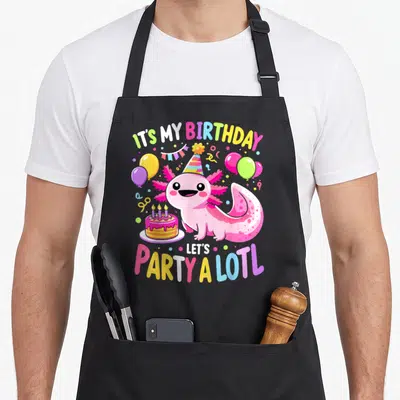 Birthday kawaii apron - Pink axolotl with party hat, balloons, cake, and text IT'S MY BIRTHDAY LET'S PARTY A LOTL — shown on a black cotton canvas apron against a white background