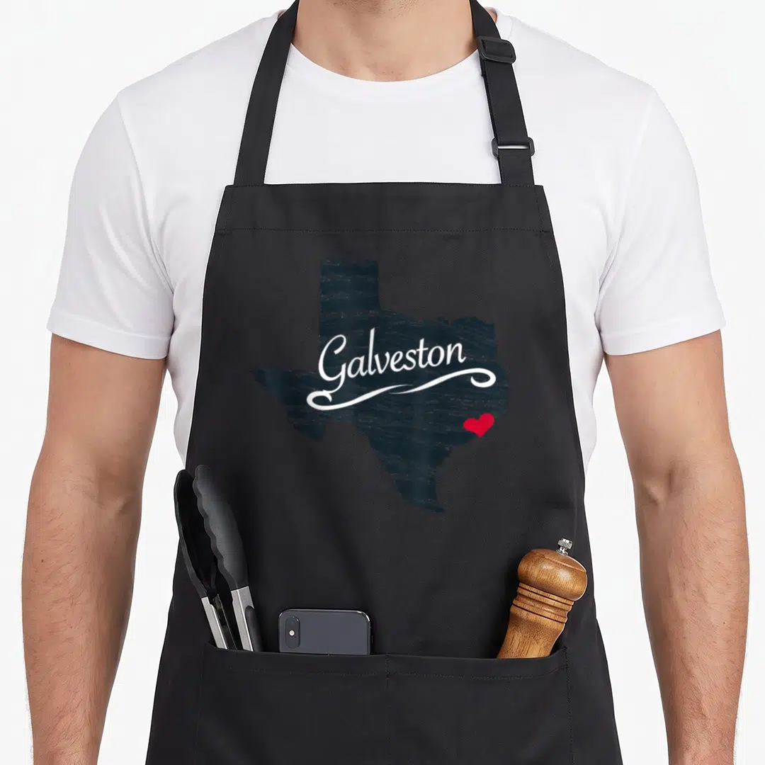 Funny galveston texas apron - Distressed blue Texas map with white Galveston script and red heart — shown on a black cotton canvas apron against a white background