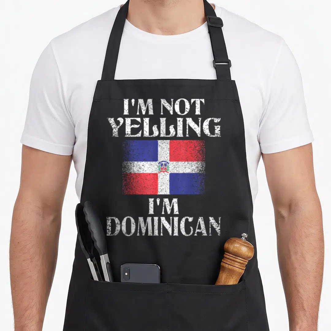 Yelling dominican pride apron - Distressed Dominican Republic flag with white stacked text reading I'm Not Yelling I'm — shown on a black cotton canvas apron against a white background