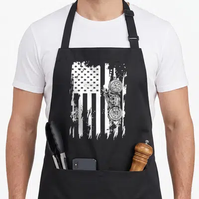 Detailed motorcycle apron - White distressed USA flag with vertical motorcycle print overlapping stripes, no text — shown on a black cotton canvas apron against a white background