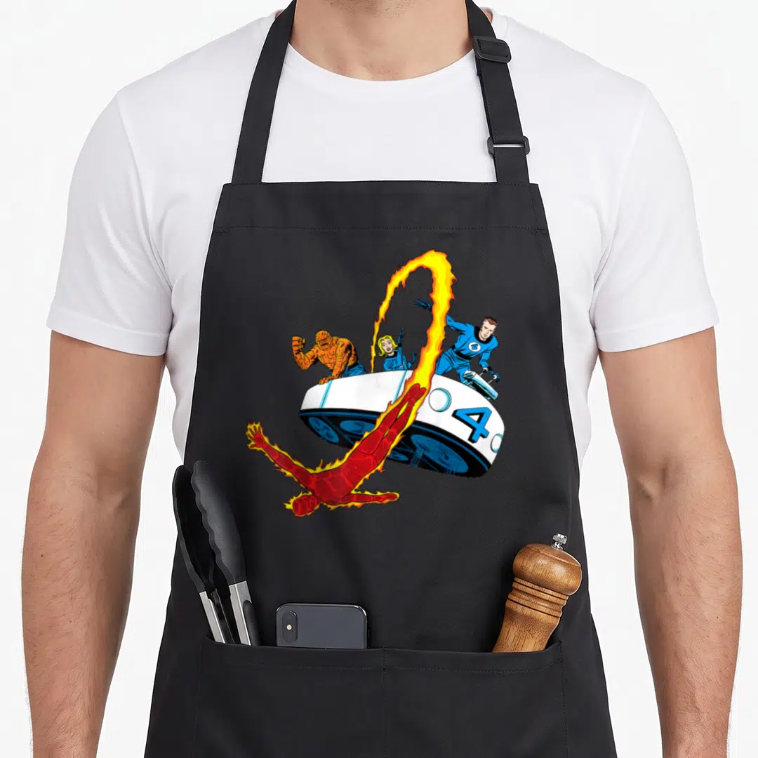 Fantastic fourth apron - Cartoon superhero team on white spaceship with blue four and flaming character flying below — shown on a black cotton canvas apron against a white background