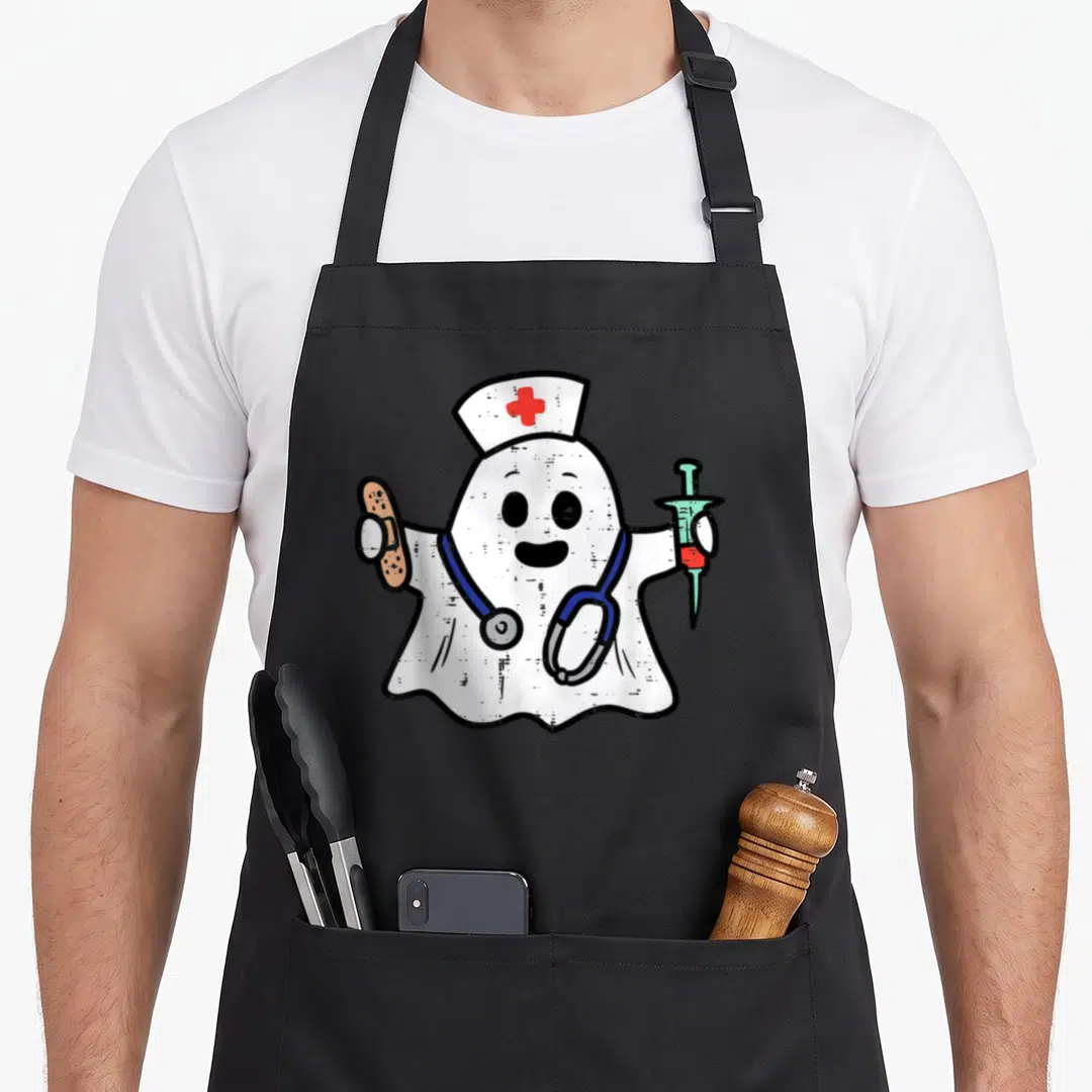 Ghost halloween nurse apron - Cartoon ghost nurse with red cross hat, blue stethoscope, tan bandage, and syringe — shown on a black cotton canvas apron against a white background