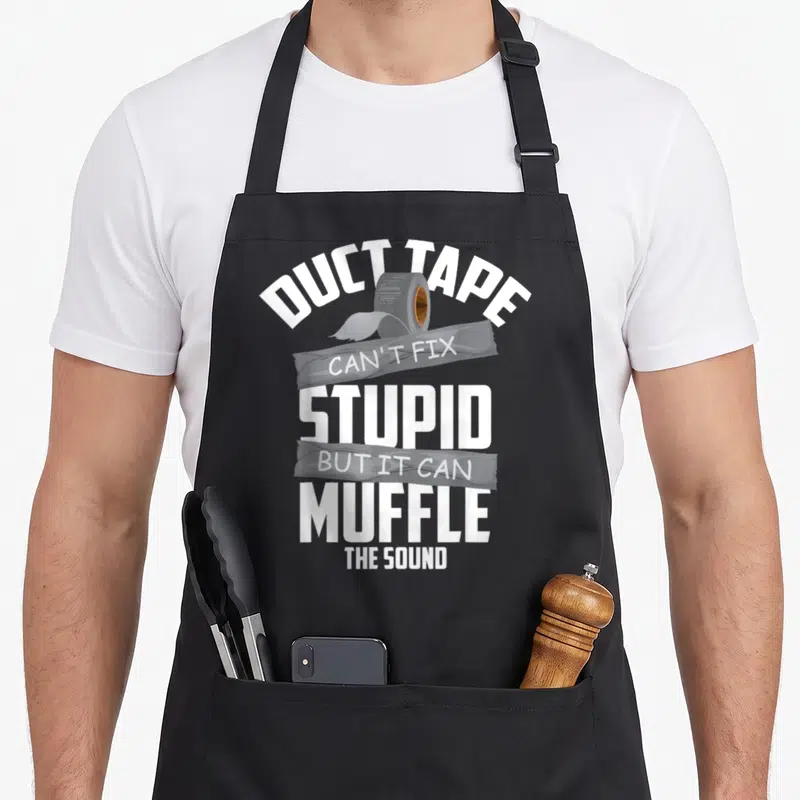 Tape stupid aprons - Duct tape roll graphic with stacked white and grey text reading can't fix stupid but muffle sound — shown on a black cotton canvas apron against a white background