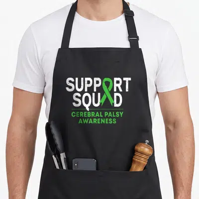 Squad ribbon apron - Green ribbon and white SUPPORT SQUAD CEREBRAL PALSY AWARENESS text on canvas — shown on a black cotton canvas apron against a white background