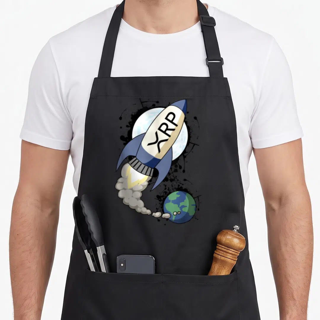 Xrp arugula apron - Cartoon rocket with XRP text launching past moon and earth with black ink splatters — shown on a black cotton canvas apron against a white background