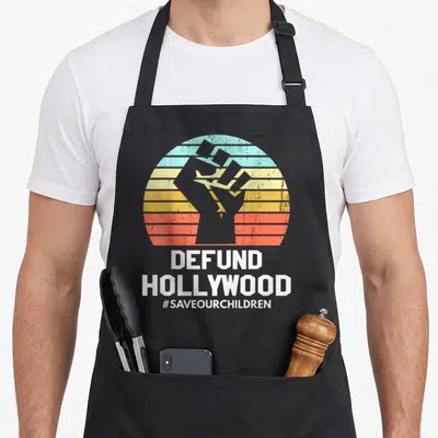 Defund vintage sunset apron - Grey raised fist over striped sunset with DEFUND HOLLYWOOD text — shown on a black cotton canvas apron against a white background