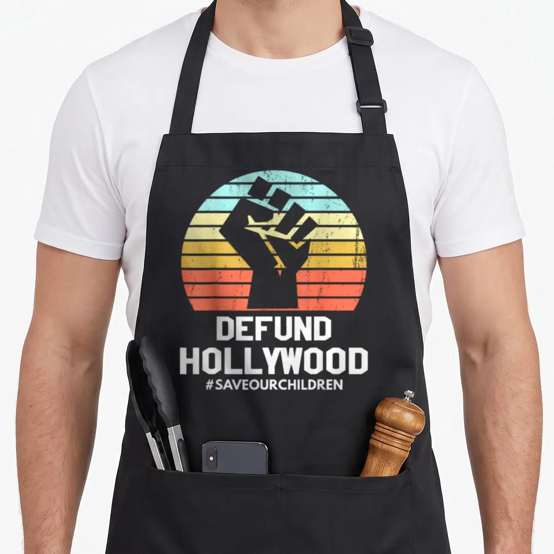 Defund vintage sunset apron - Grey raised fist over striped sunset with DEFUND HOLLYWOOD text — shown on a black cotton canvas apron against a white background