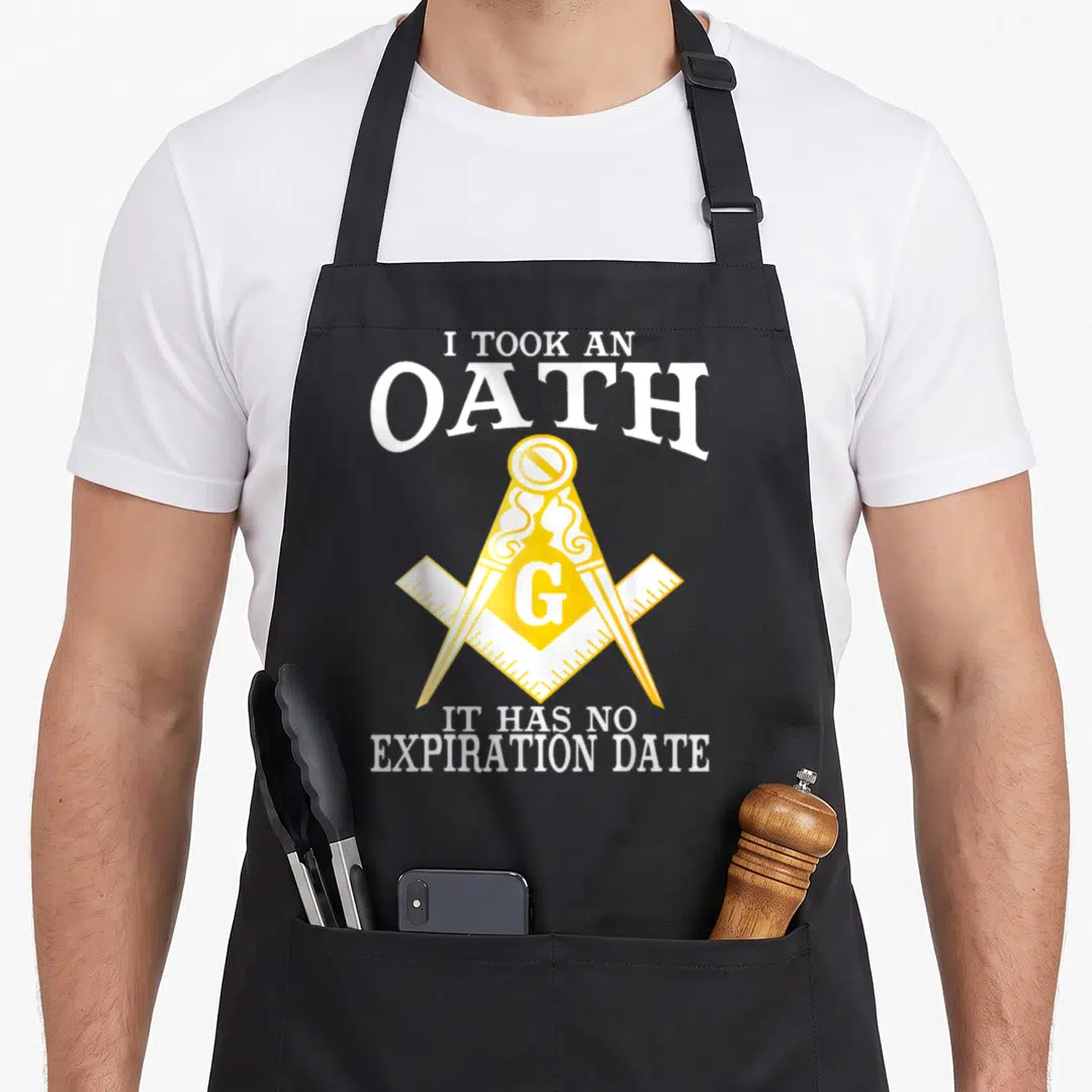 Took mason apron - I Took An Oath text above and below yellow square compass with G on grey background — shown on a black cotton canvas apron against a white background