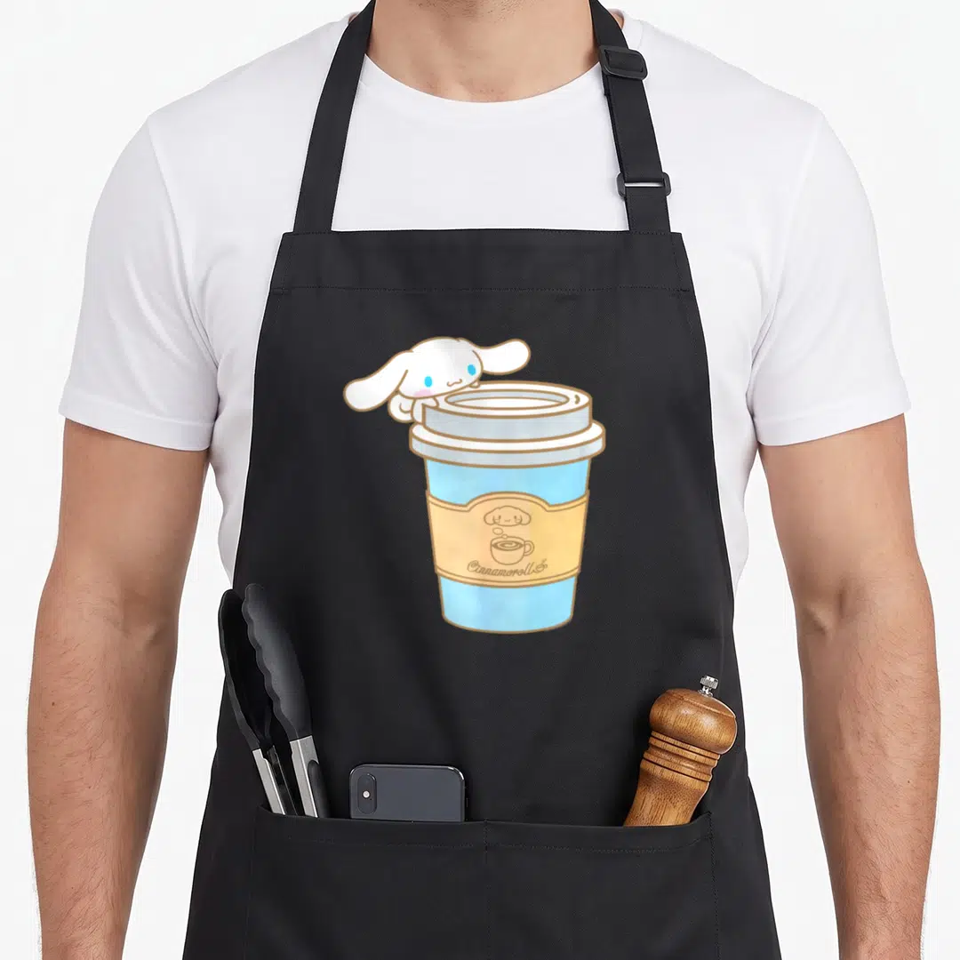 Cinnamoroll coffee apron - White cartoon character peeking over blue coffee cup with brown sleeve logo — shown on a black cotton canvas apron against a white background