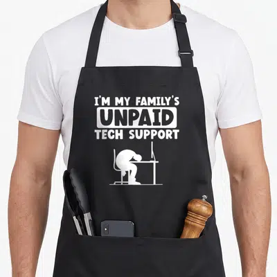 Unpaid family aprons - White text reading I'm My Family's Unpaid Tech Support above a slumped person silhouette — shown on a black cotton canvas apron against a white background