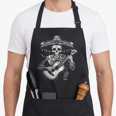 Guitar day of the dead apron - White line-art skeleton in sombrero and poncho playing a guitar — shown on a black cotton canvas apron against a white background