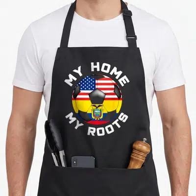 Ecuador football apron - Soccer ball split between USA and Ecuador flags with white text reading My Home My Roots — shown on a black cotton canvas apron against a white background