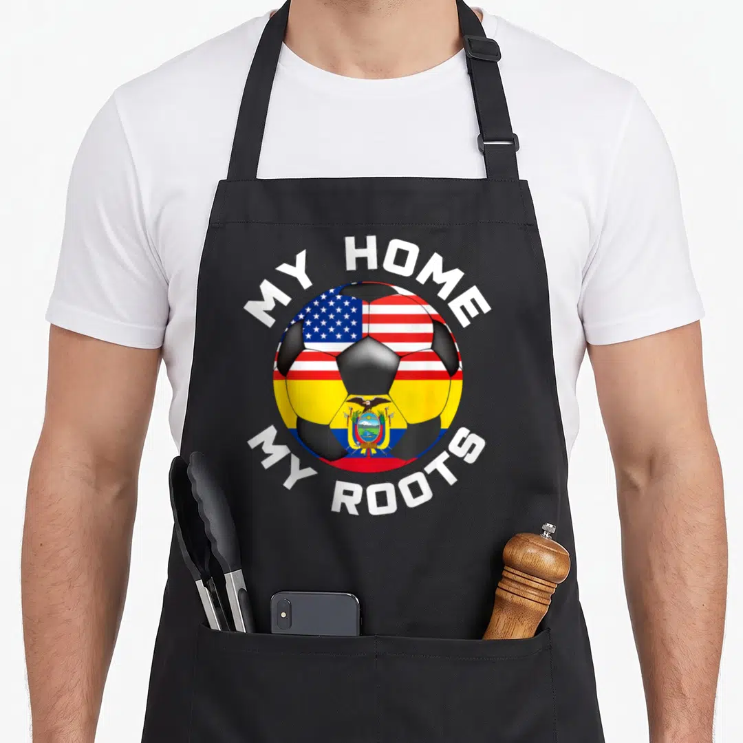 Ecuador football apron - Soccer ball split between USA and Ecuador flags with white text reading My Home My Roots — shown on a black cotton canvas apron against a white background