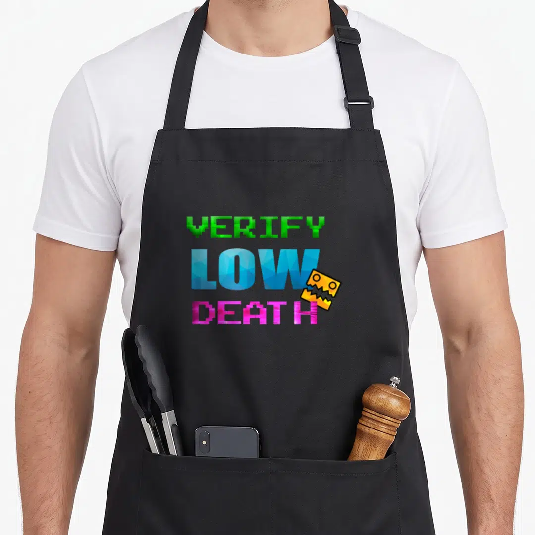 Verify game aprons - Pixel text VERIFY LOW DEATH in green blue pink with yellow monster face — shown on a black cotton canvas apron against a white background