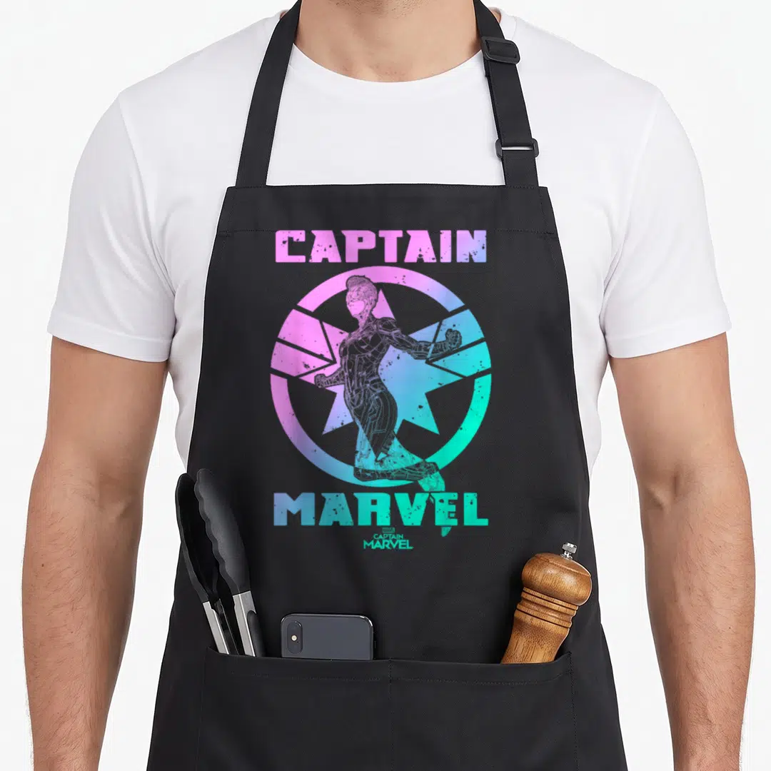 Captain miss grade apron - Retro Captain Marvel in pink blue green gradient inside star and circle badge design — shown on a black cotton canvas apron against a white background