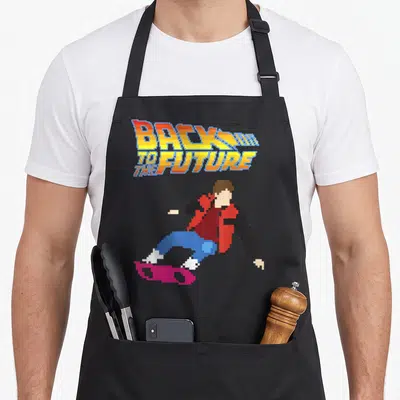 Bit future and apron - Pixelated person on pink hoverboard under stacked multicolor text logo — shown on a black cotton canvas apron against a white background