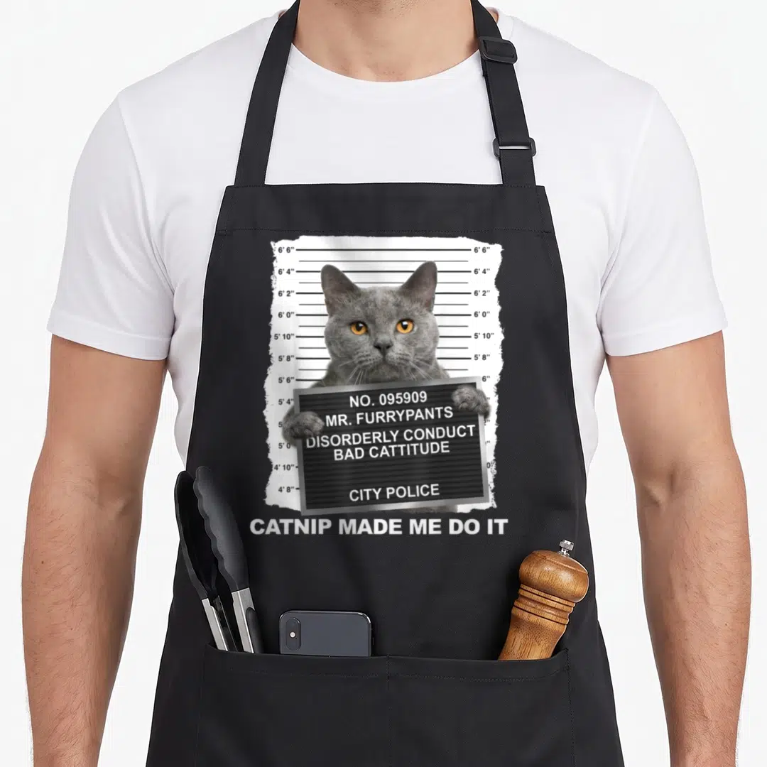 Catnip cat apron - Grey cat mugshot holding sign with height chart and catnip made me do it text — shown on a black cotton canvas apron against a white background