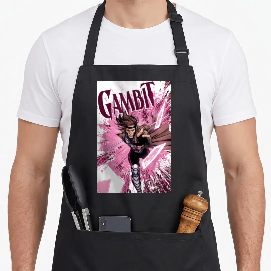 Card x apron - GAMBIT text above leaping character with staff and flying cards in pink and purple — shown on a black cotton canvas apron against a white background